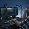 3d animation artist reviewing character render on dual monitors in dark studio with tripod and keyboard setup austin visuals