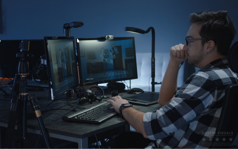 3d animation artist reviewing character render on dual monitors in dark studio with tripod and keyboard setup austin visuals