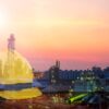 industrial facility with sunset background and overlay of yellow hard hat representing workplace safety