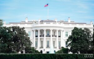 white house front view with american flag blue sky trees and fountain