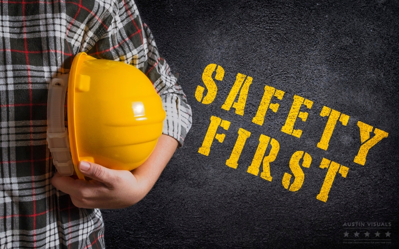 worker holding yellow hard hat with safety first text on chalkboard background